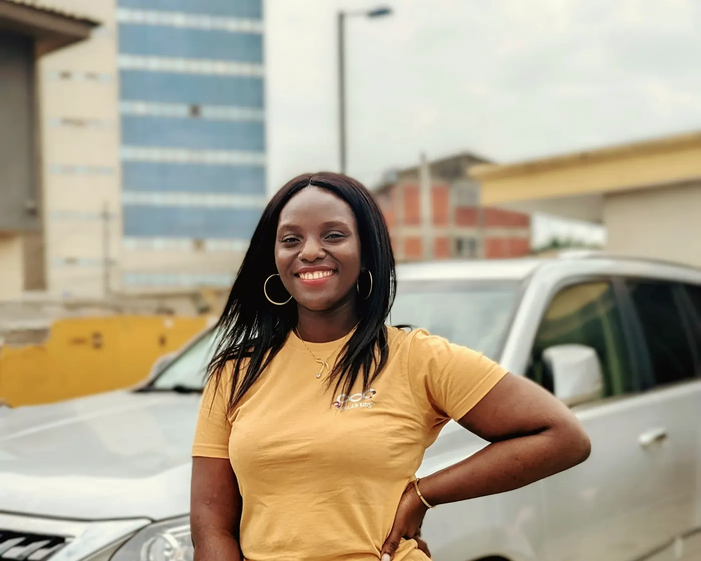 A smiling woman standing beside a car on a city street